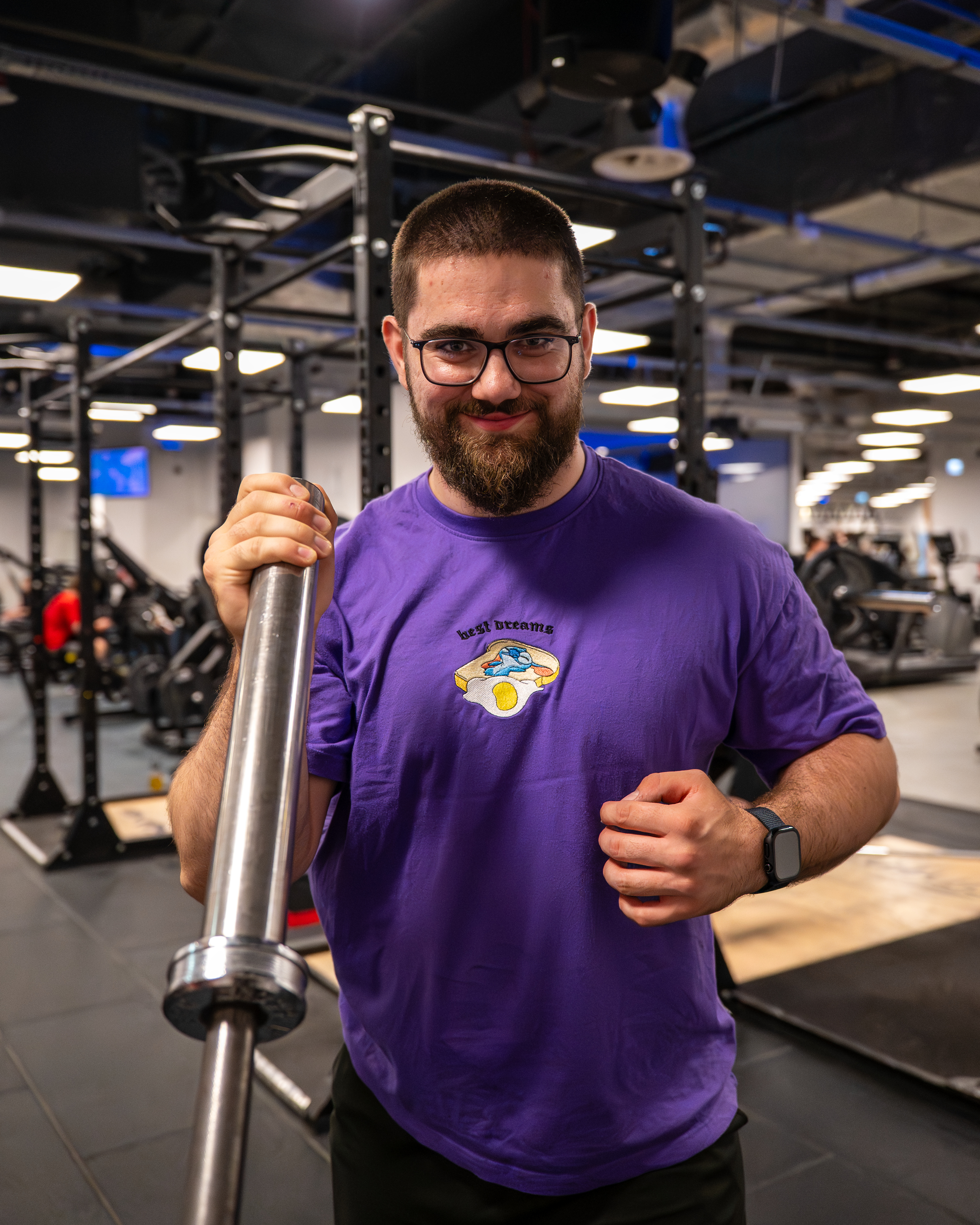 Jakub Sołoducha — trener personalny w klubie CityFit Lublin Plaza trzymający gryf
